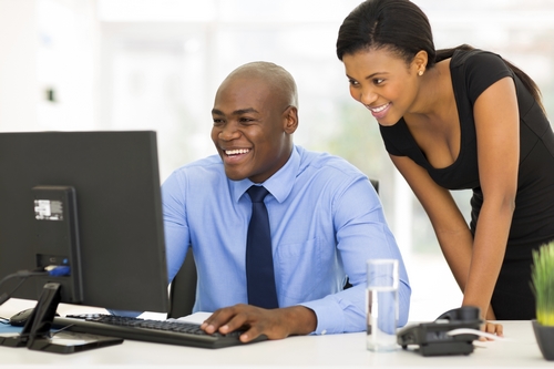 successful african secretary with her boss working on computer